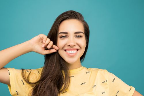 Free Cheerful young woman smiling brightly against an aqua background. Stock Photo