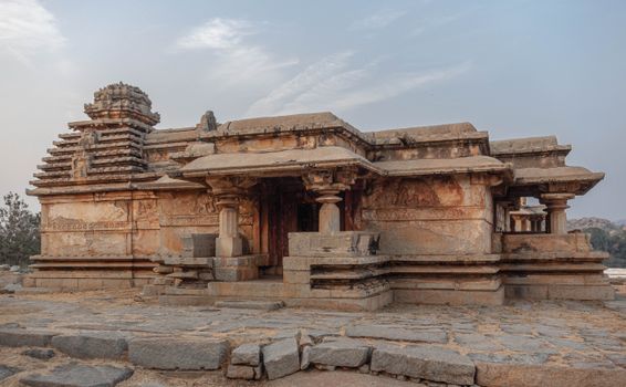 Explore the stunning stone architecture of a historic temple in Hampi, India, showcasing intricate carvings and ancient design.