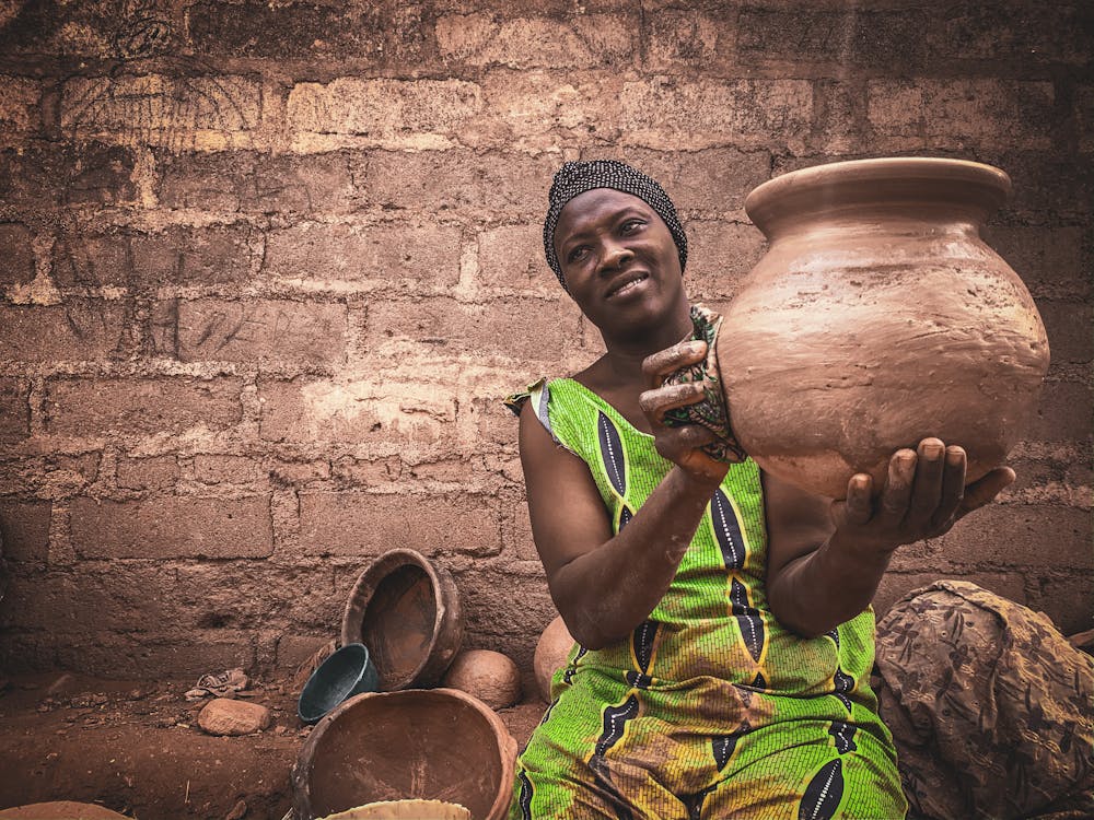 African woman showing handicraft earthenware in local workshop