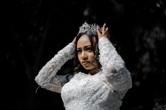 Concentrated ethnic woman in wedding dress and crown before ceremony