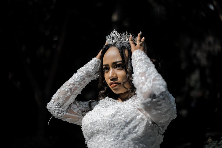 Concentrated Ethnic Woman In Wedding Dress And Crown Before Ceremony