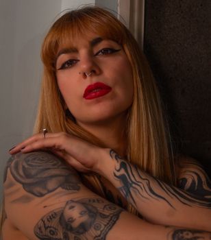 Close-up portrait of a woman with tattoos and bold makeup, exuding confidence.