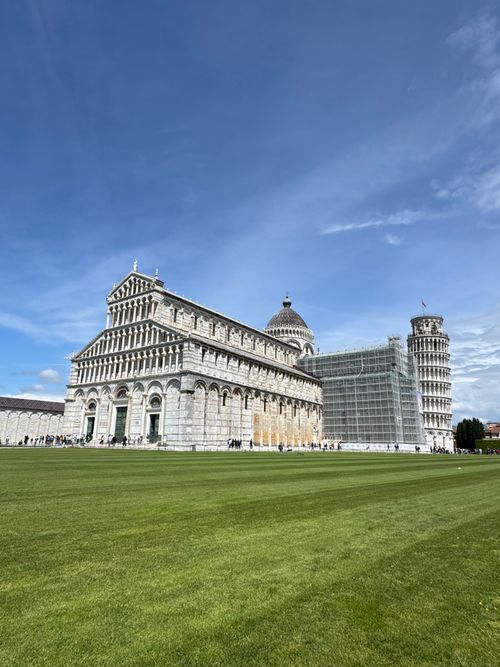 Free Scenic view of the Leaning Tower of Pisa and Pisa Cathedral against a vibrant blue sky. Stock Photo