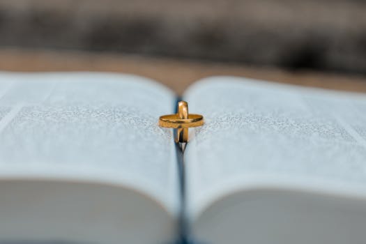 A close-up of a gold wedding ring placed on an open book, symbolizing union and tradition.