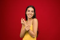 一位开朗的女人穿着黄色背心，在充满活力的红色背景下摆姿势