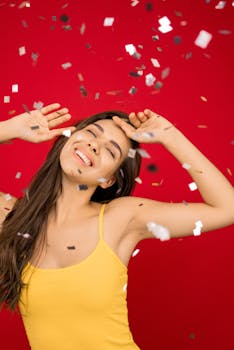 一位微笑的女子在五彩纸屑和充满活力的红色背景下享受庆祝活动