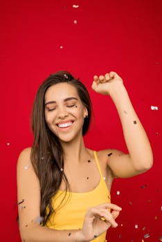 在红色背景上，快乐的女人在黄色顶部庆祝，周围飘洒着五彩纸屑