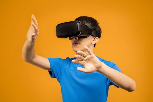 Man in Blue Crew Neck T-shirt Wearing Black VR Goggles