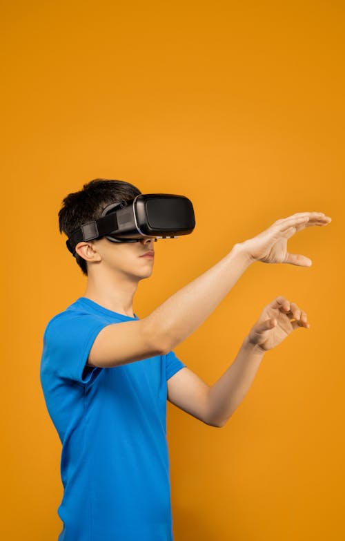 Man in Blue Crew Neck T-shirt Wearing Black VR Goggles