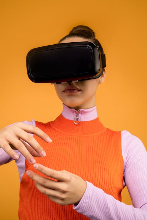 Woman in Orange and Pink Long Sleeve Shirt Wearing VR Goggles