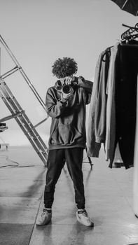 Black and white image of a young photographer taking a picture in a studio.