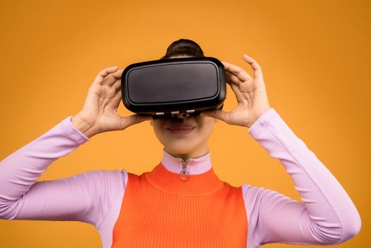 Woman in Orange and Pink Long Sleeve Shirt Holding Black and Gray Vr Gadget