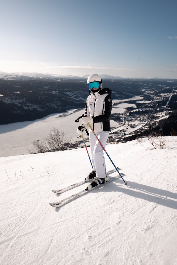 Person In White Jacket And White Pants Riding Ski Blades On Snow Covered Mountain