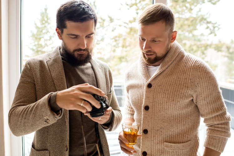 Man In Brown Coat Holding Black Dslr Camera