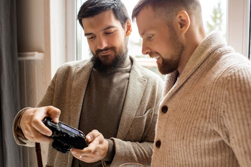 黒のカメラを保持している茶色のボタンアップコートの男