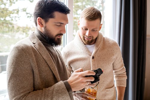 Man in Brown Sweater Holding Black Dslr Camera