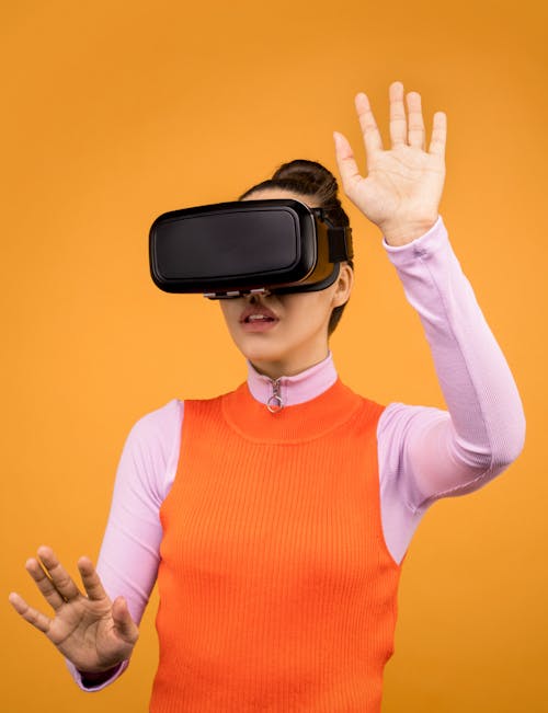 Woman in Orange and Pink Long Sleeve Shirt Wearing Black Vr Goggles