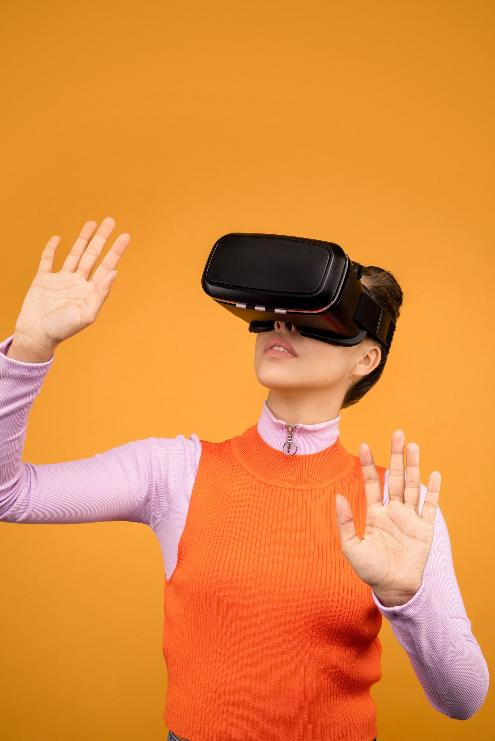 An adult wearing a virtual reality headset against a bright orange background