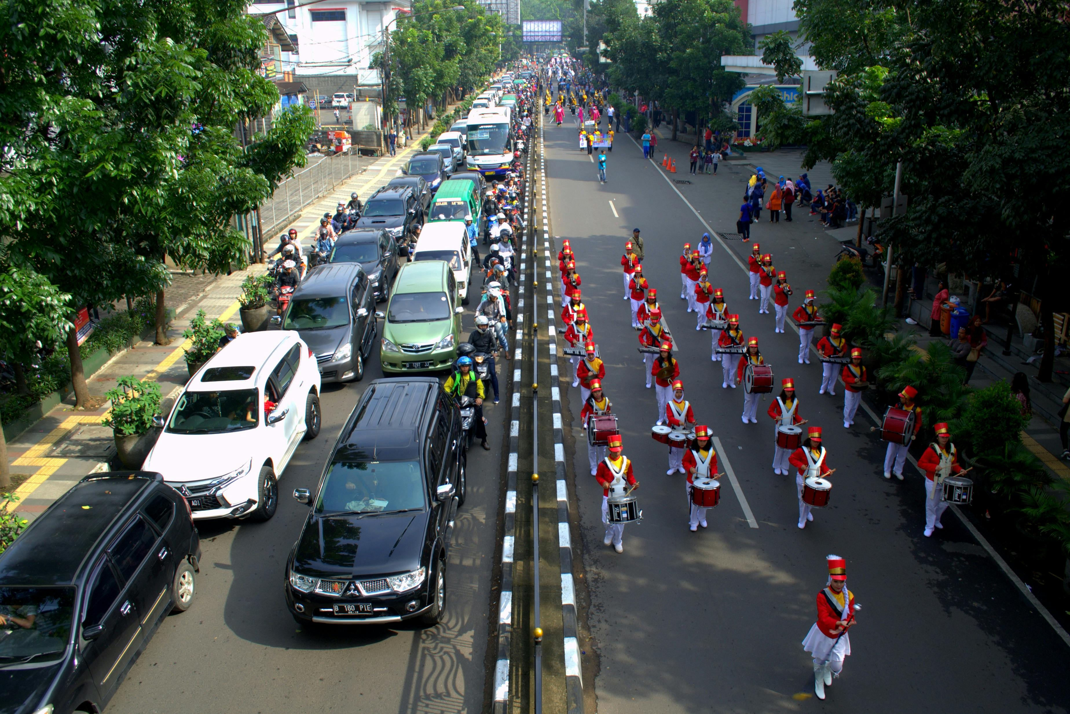A lively marching band parade in Bandung, West Java, showcasing cultural traditions and crowd engagement.