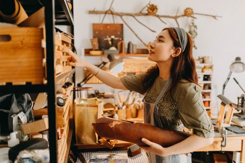 Free Young artisan woman works in a cozy studio crafting leather goods, showcasing creativity and craftsmanship. Stock Photo