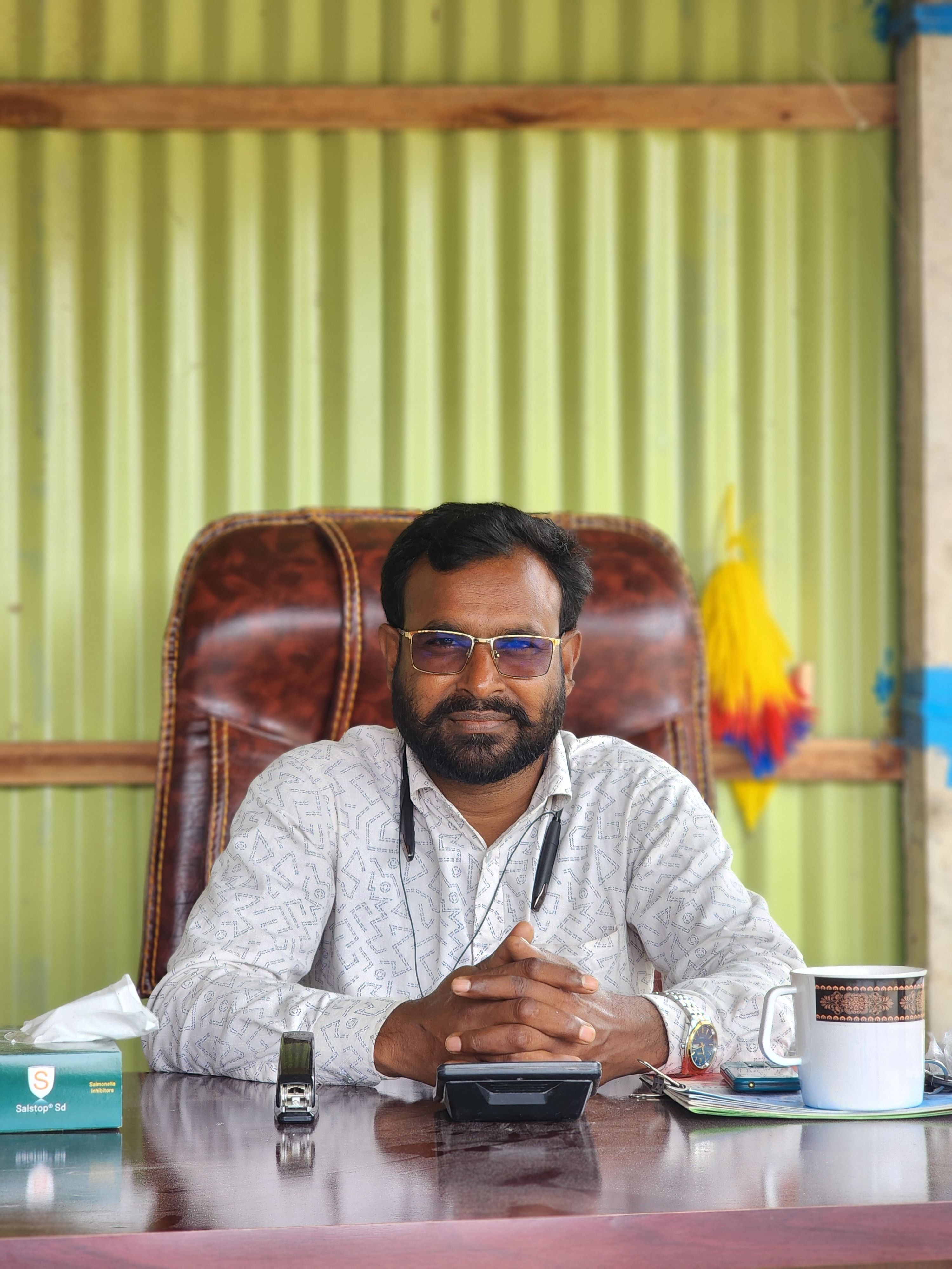 A confident businessman sitting at his office desk with various items around.