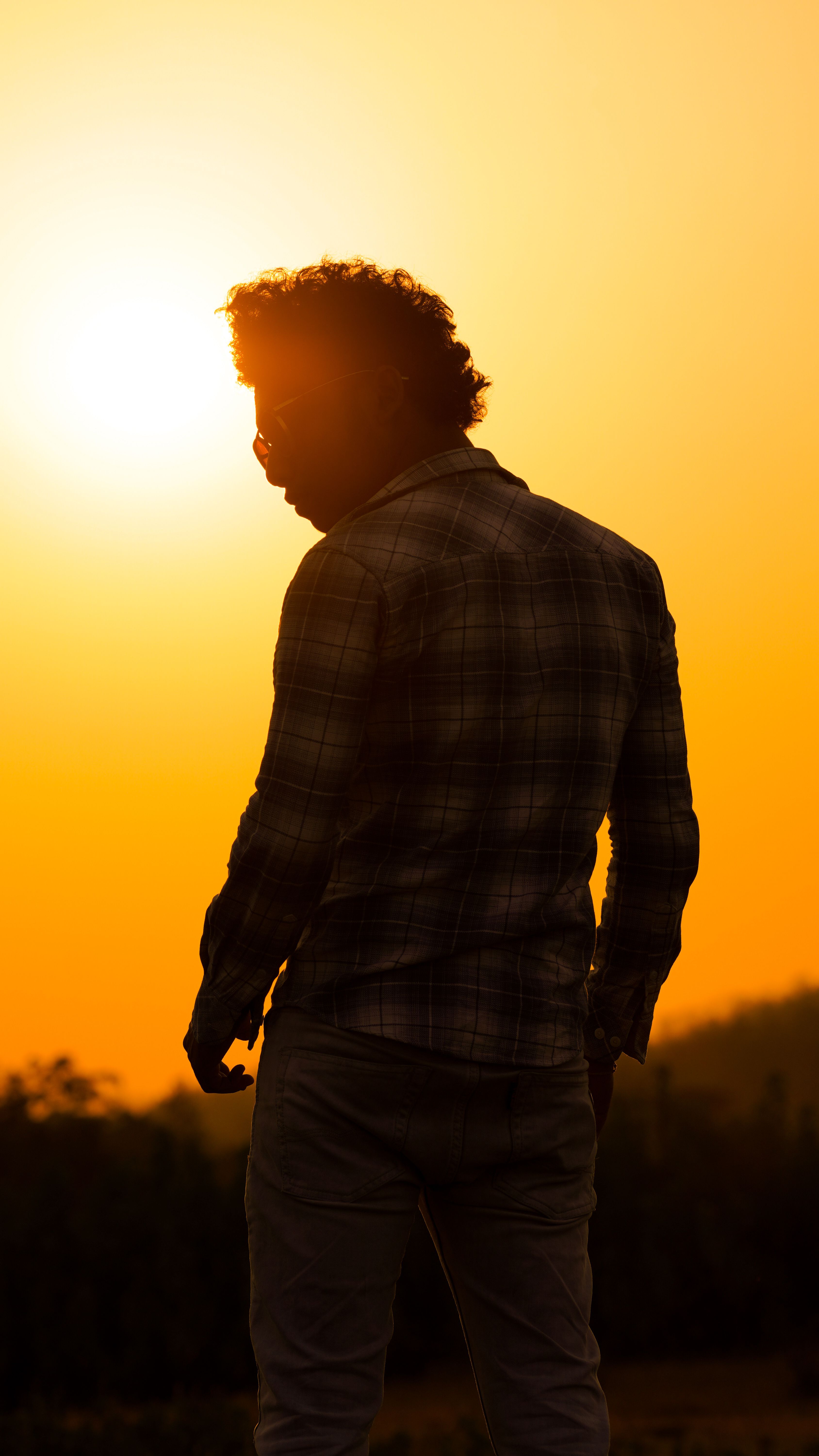 Silhouette of a man standing outdoors against a vibrant sunset sky. Perfect for concepts of reflection and solitude.