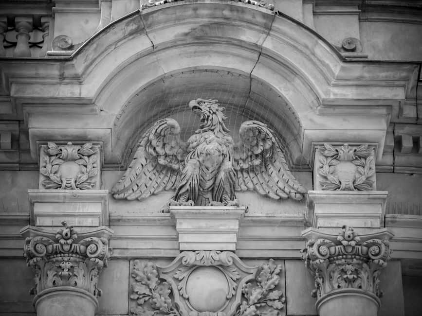 Black and white image of an ornate eagle sculpture on a historic Polish building facade.