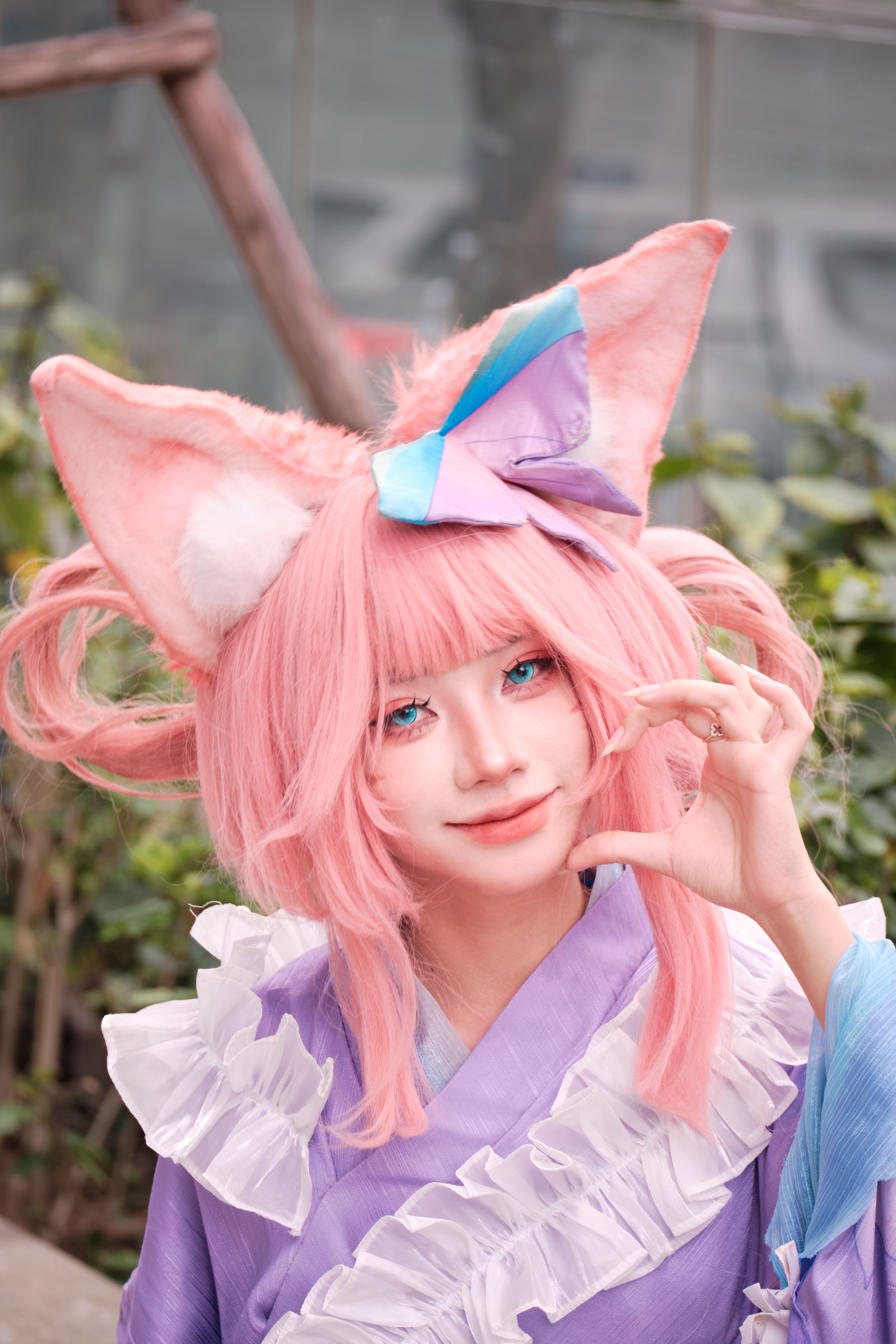 A vibrant cosplayer in a pink anime costume posing outdoors.