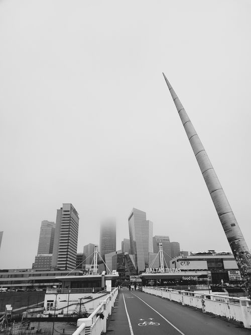 Free Foggy skyline of modern skyscrapers in Vilnius, Lithuania with iconic spear sculpture. Stock Photo
