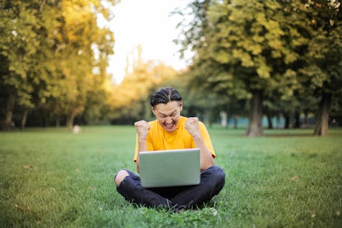 Free Man Sitting on a Green Grass Field Stock Photo