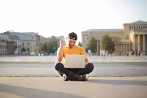 Mann Im Weißen T Shirt Und In Der Schwarzen Hose, Die Auf Der Straße Mit Laptop Computer Sitzen