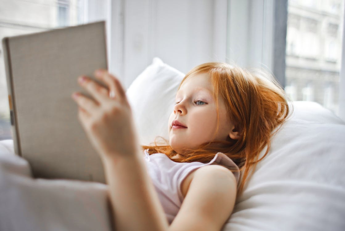 Free A Girl Reading A Book While Lying On Bed Stock Photo