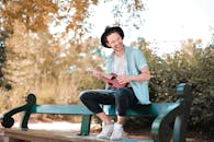 Man Sitting on Wooden Bench Using Ukulele