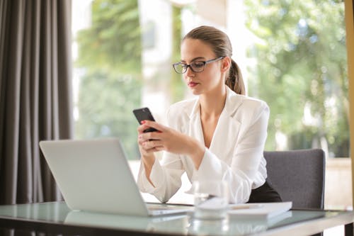 Femme D'affaires Sérieuse à L'aide De Smartphone En Milieu De Travail