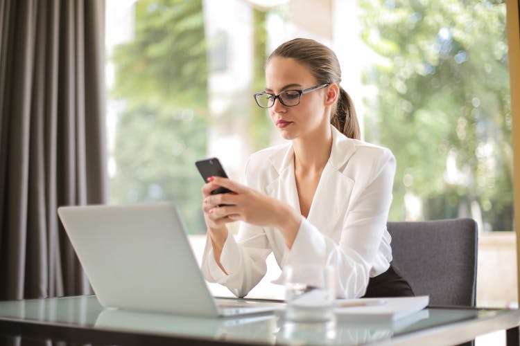 Serious Businesswoman Using Smartphone In Workplace