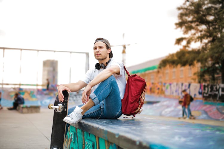 Young Skater With Backpack Sitting On Ramp