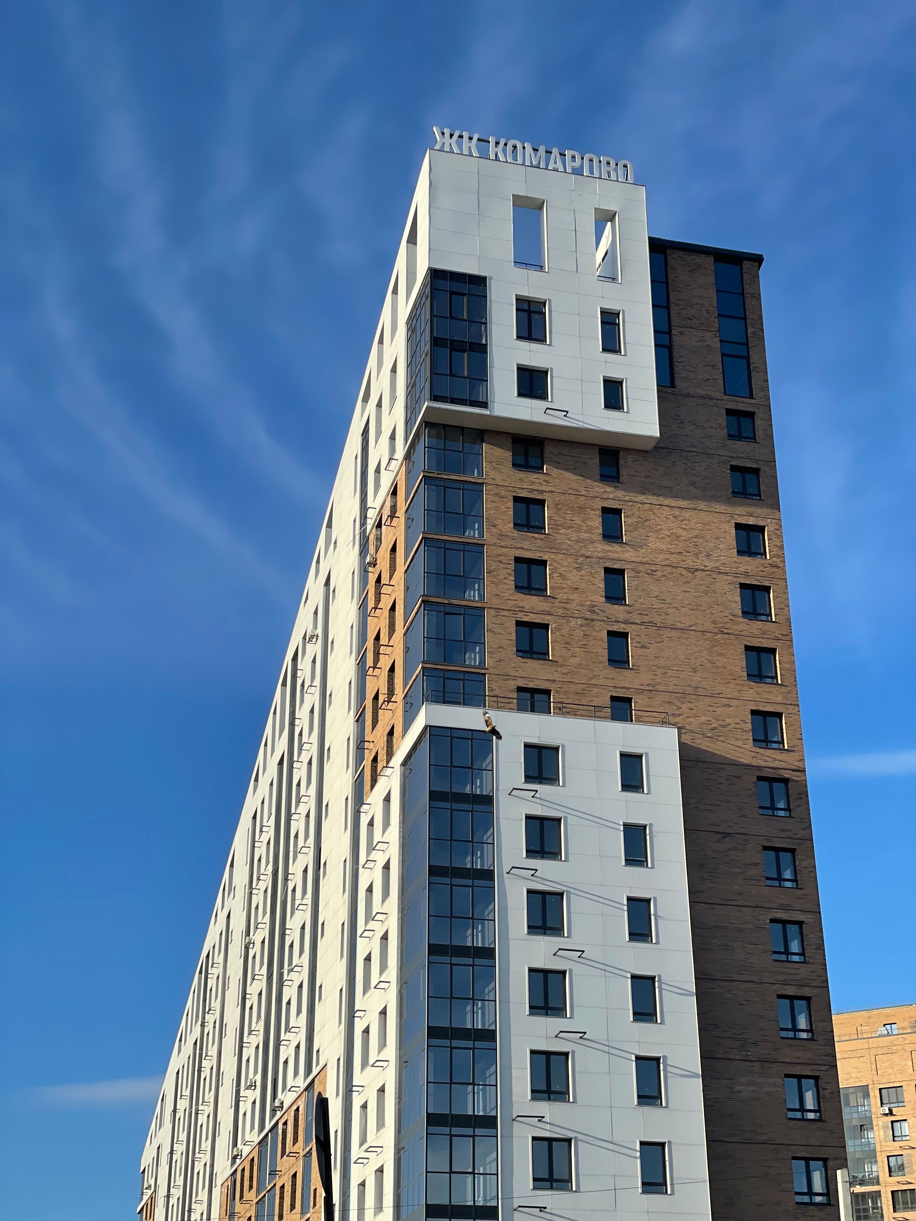 Modern high-rise apartment building against a clear blue sky, showcasing urban architecture.