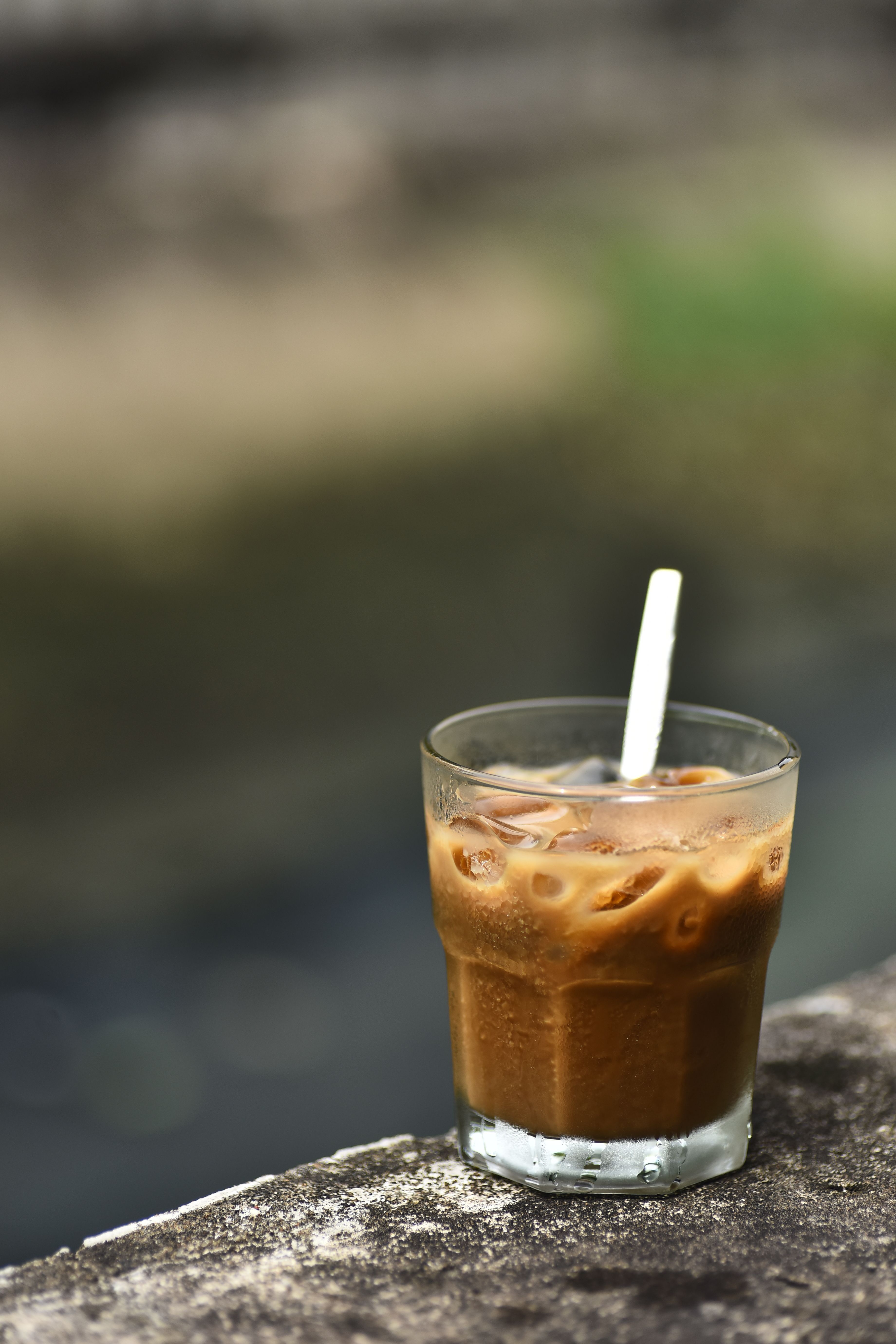 A refreshing glass of iced coffee with a straw in an outdoor setting. Perfect for a warm summer day.