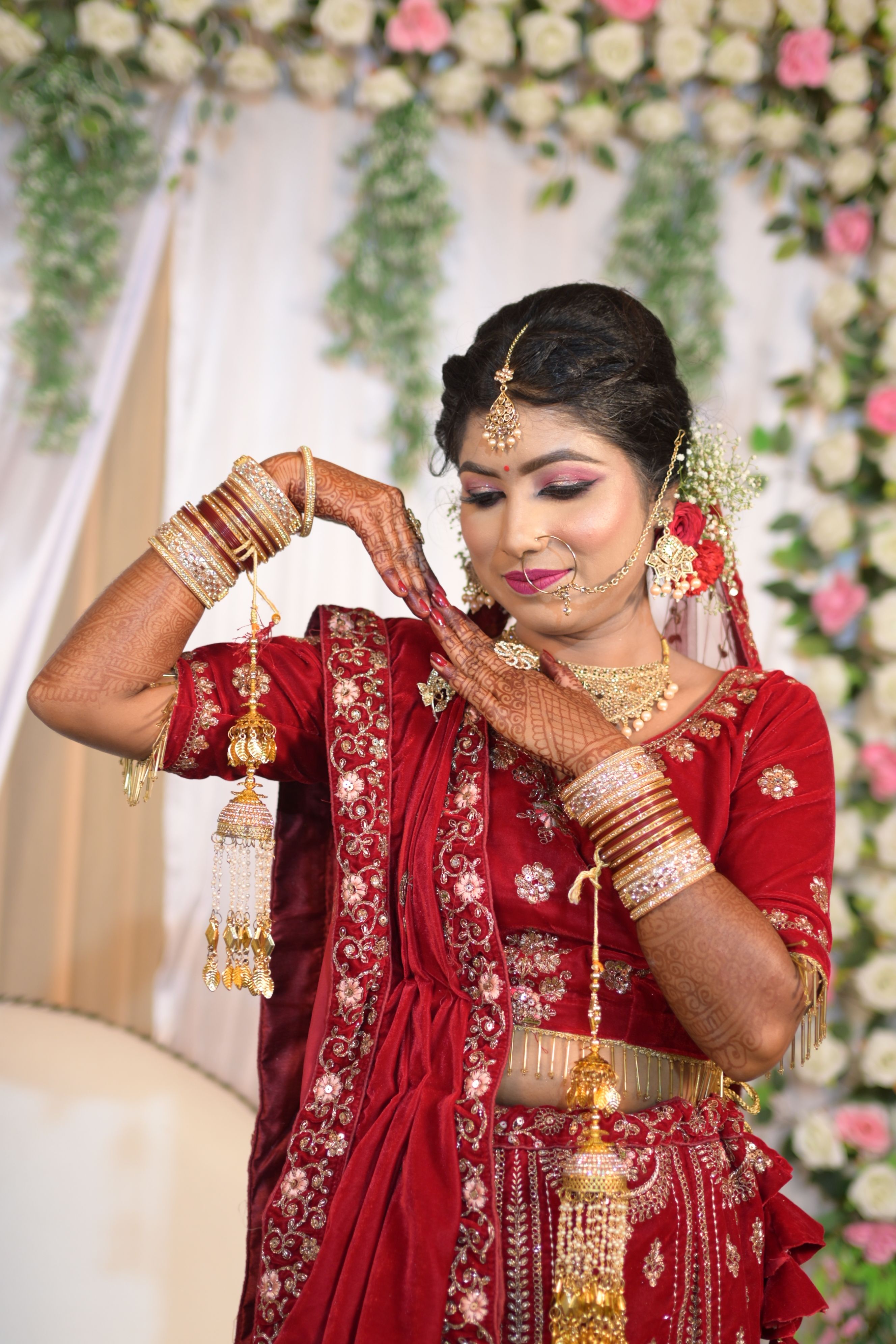 Beautiful Indian bride posing gracefully in red bridal lehenga with intricate jewelry.