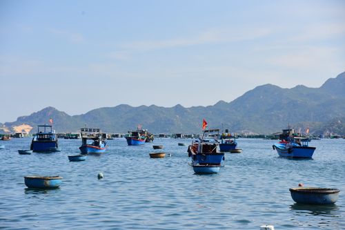 Free Fishing boats float peacefully on a calm sea with a beautiful mountain backdrop. Stock Photo