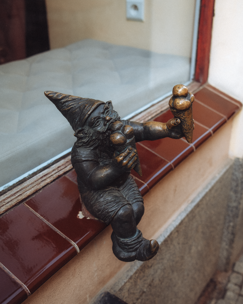 Free Bronze gnome statue with two ice cream cones on a window ledge in Breslau, Poland. Stock Photo