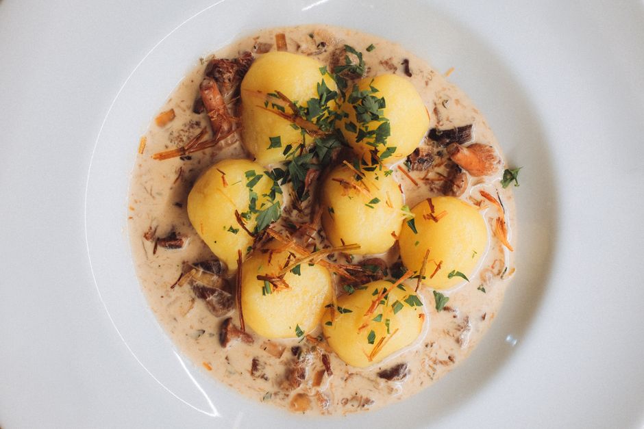 Close-up of traditional Polish dumplings served with a savory cream and mushroom sauce, garnished with fresh parsley.