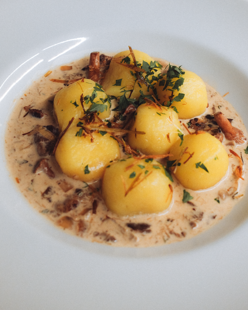 Free Polish potato dumplings served with creamy mushroom sauce, garnished with herbs. Stock Photo