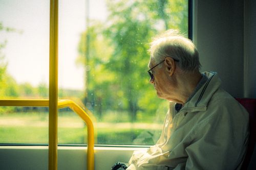 Free Senior man reflecting while looking out from tram window during a sunny spring day. Stock Photo