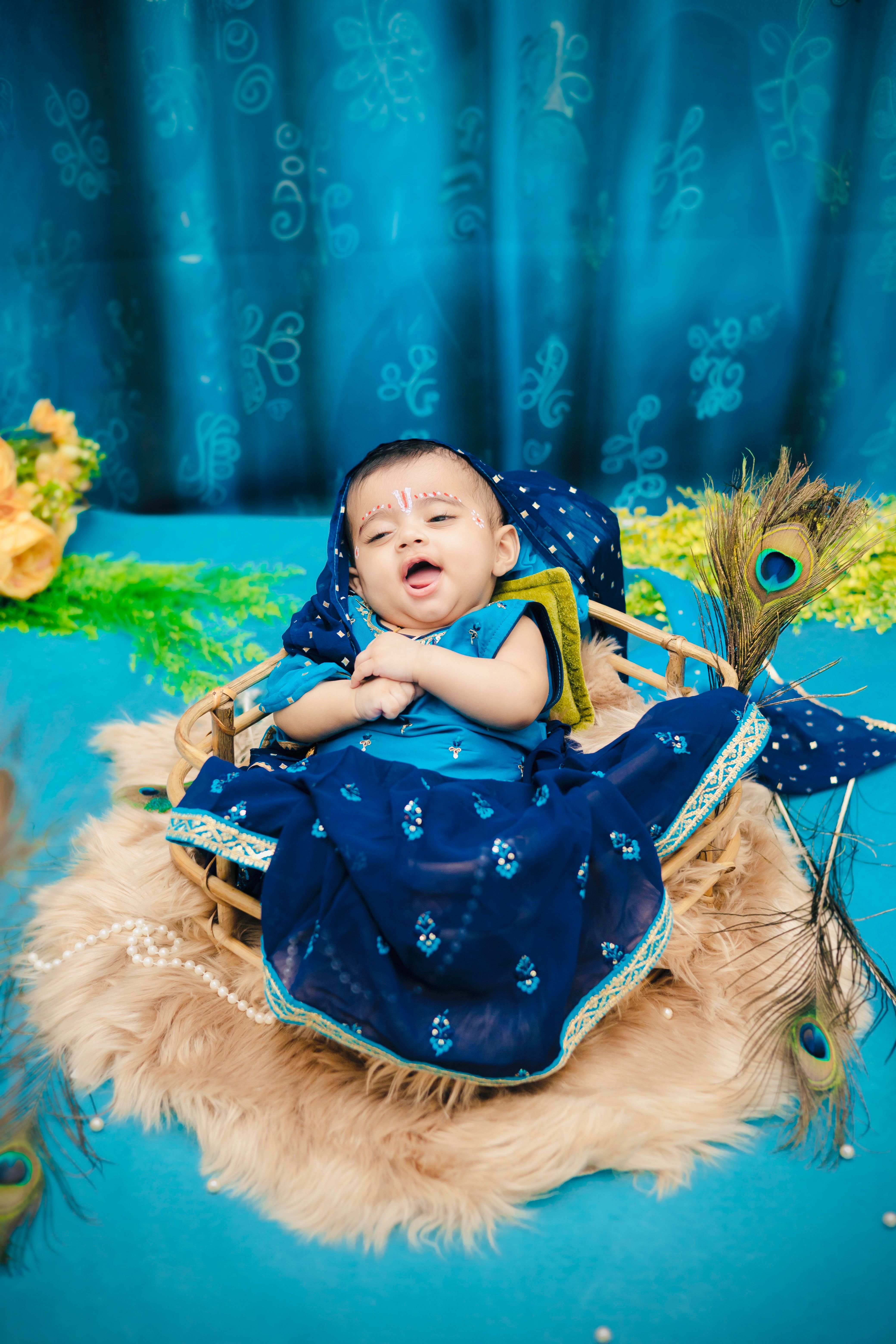 Charming baby dressed as Lord Krishna for Janmashtami celebration indoors.