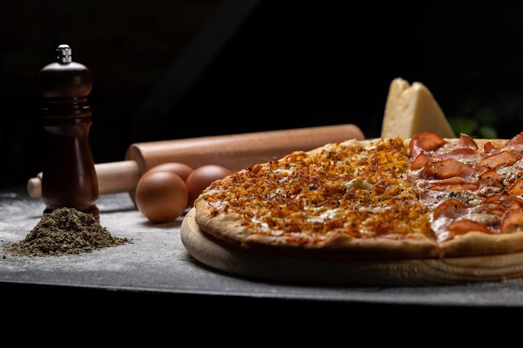 Pizza On Wooden Board Beside Eggs And Rolling Pin