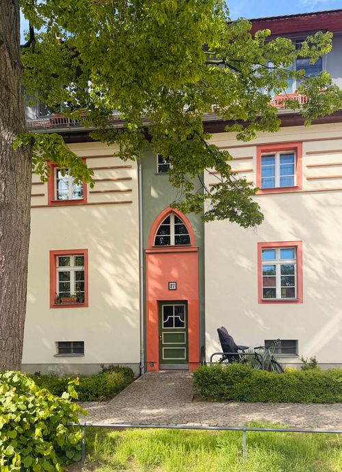 Free Charming European house with colorful facade and a bicycle parked outside, under a tree. Stock Photo