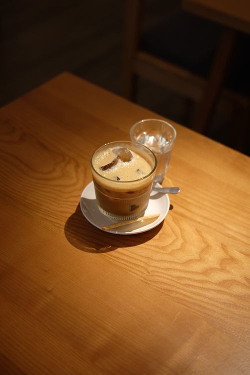 Free A refreshing glass of iced coffee on a wooden table accompanied by a glass of water, perfect cafe ambiance. Stock Photo