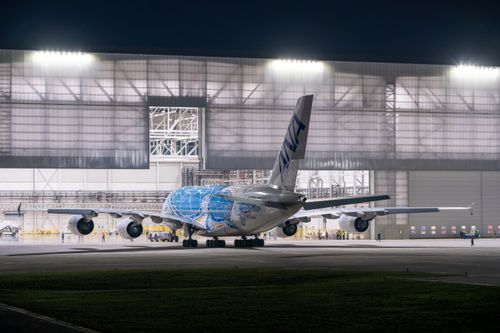 Free A large airplane with unique design parked in a lit hangar during nighttime. Stock Photo