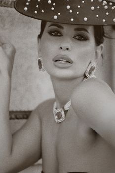 Stunning elegant woman wearing vintage hat and jewelry in a classic portrait style.